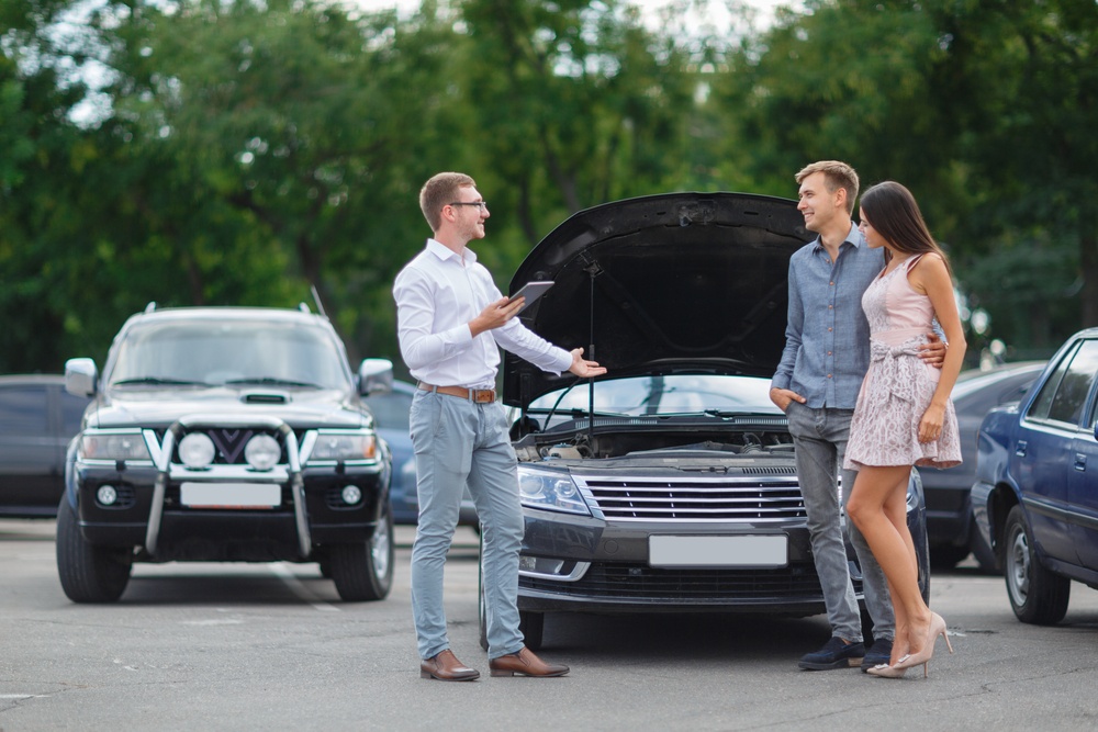 A young man selling a car to a couple