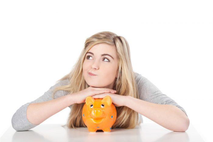 Young teen girl holding a piggy-bank as an example of jobs for high school students