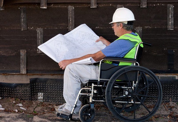 Man in a wheelchair reading blueprints as an example of jobs for people with disabilities