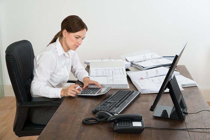 Woman busily working at her desk adding numbers on a calculator as an example of jobs for people with aspbergers