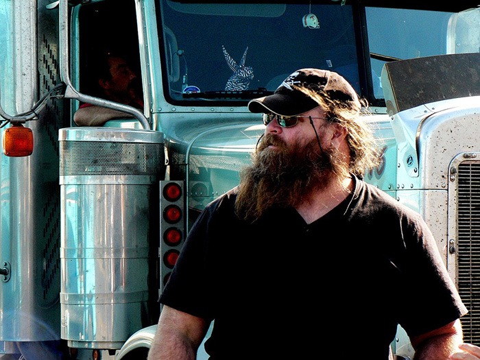 Bearded man standing in front of a truck as an example of jobs for people with criminal records