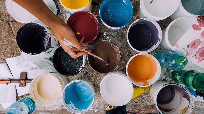 A collage of buckets of paint containing different colors as an example of jobs for artists