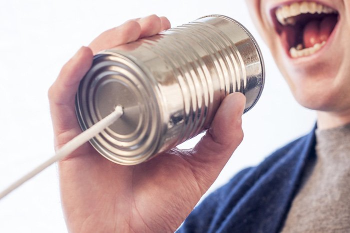 Man speaking into a tin can toy as an example of jobs for communications majors