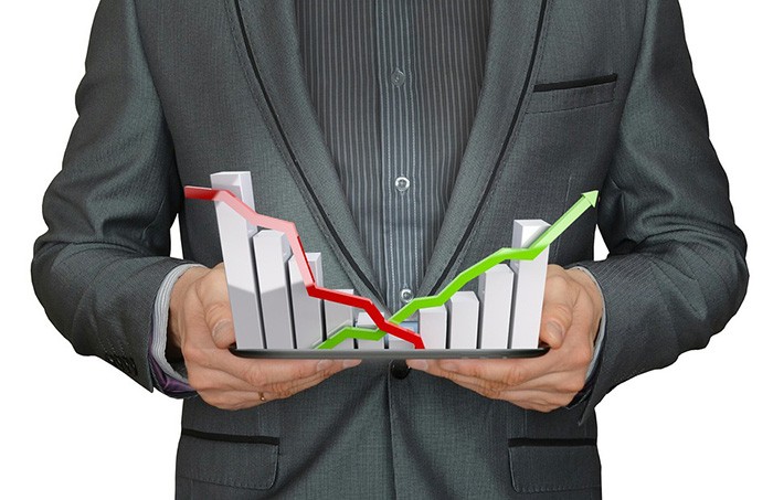 Man in a suit holding a bar graph in both hands representing economics data