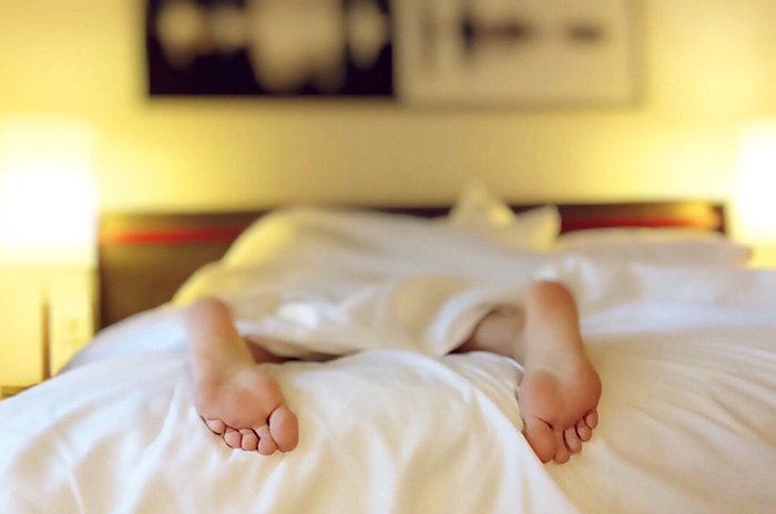 Woman sleeping on a bed under the covers as an example of a burnt out nurse