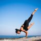 Woman on a rock with the ocean in the background doing yoga as an example of jobs in kinesiology