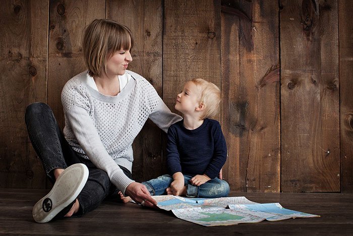 Young mom sitting on the floor with her child looking lovingly into his eyes as an example of jobs for nurses who are moms