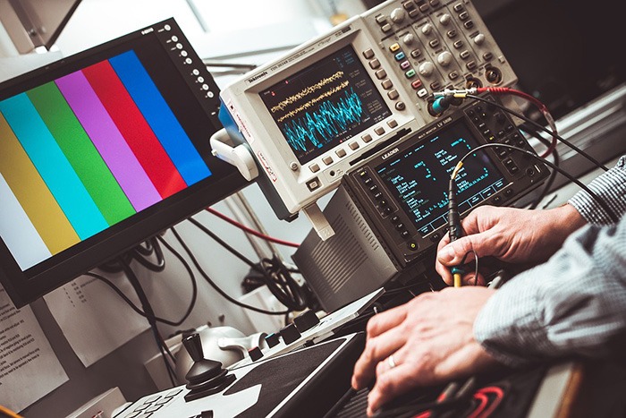 Man using a tool to take readings from electrical equipment as an example of a job as an electrical engineer