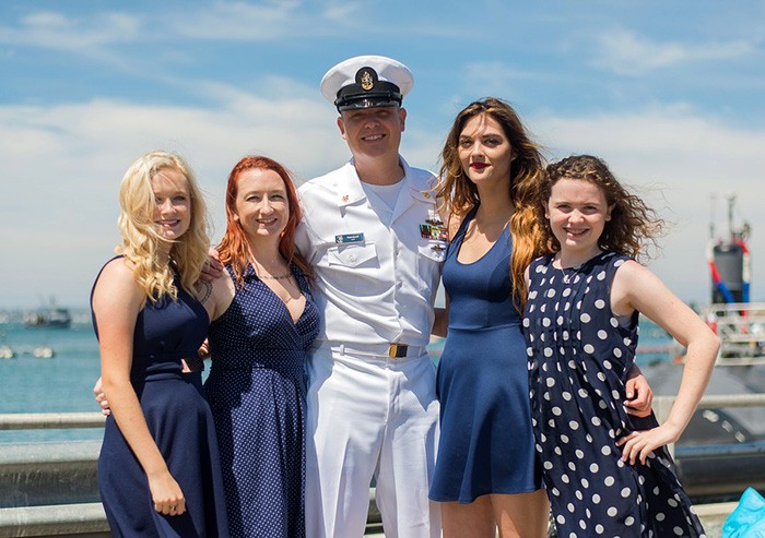 Man in military uniform posing for a picture with his family as an example of a veteran