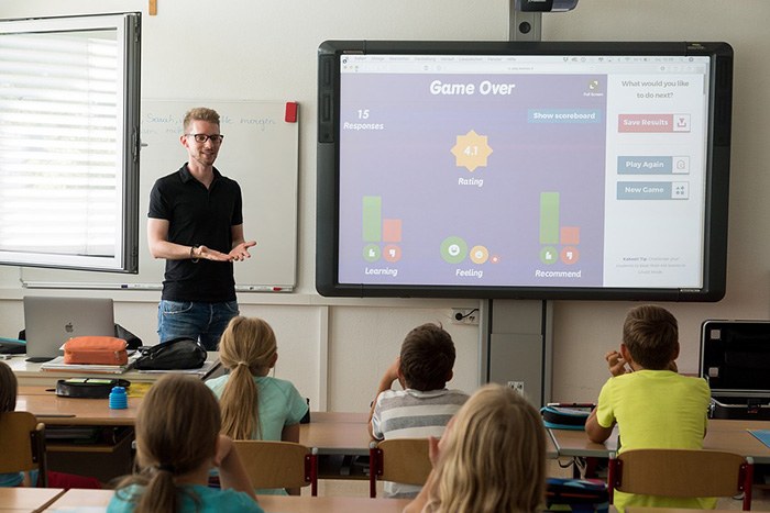 Teacher standing in front of a chalkboard teaching students in a class