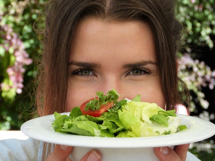 Woman holding a plate of salad as an example of working as a nutritionist