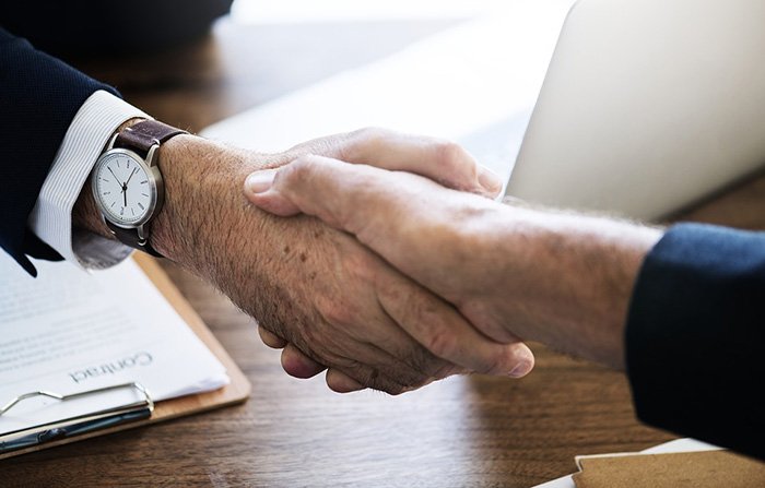 Two men shaking hands after a job interview as an example of an older worker being hired for his second career