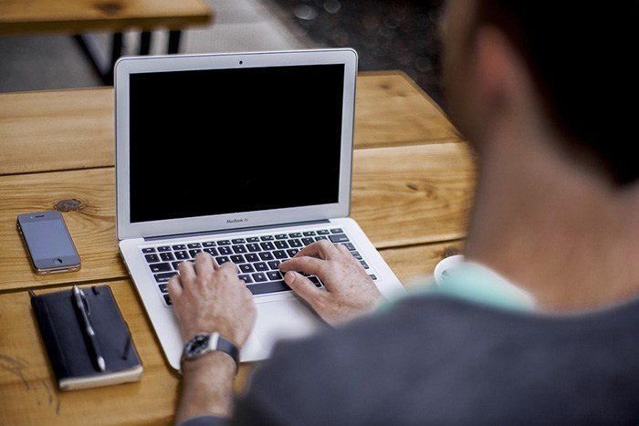 Photo of a man typing on a computer as an example of getting paid to write opinion articles