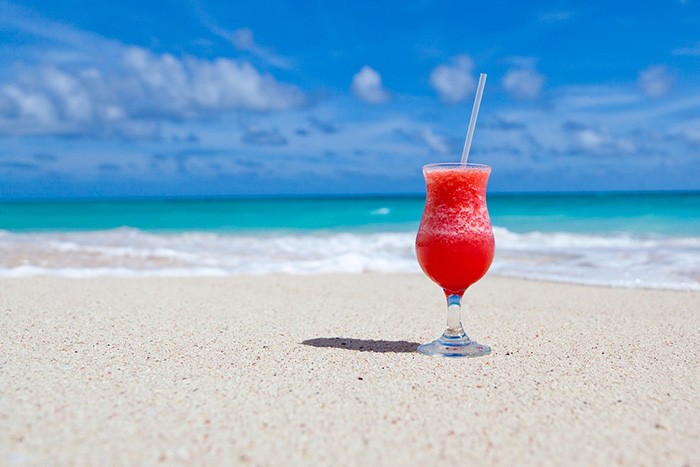 Photo of a fruity drink on a beach as an example of travel jobs