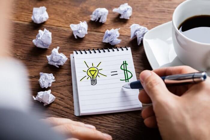 image of lightbulb and dollar sign on scratch paper showing a person thinking of ideas of how to make money