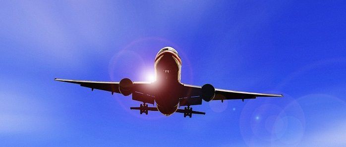 Image of a commercial plane coming into land against a blue sky.