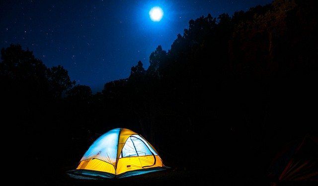 lighted tent under moonlight in the forest representing the best outdoors affiliate programs