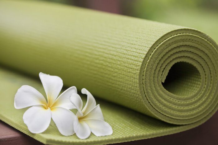 green yoga mat with white flower representing the best yoga affiliate programs