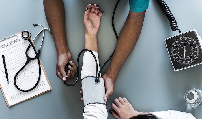 black doctor or nurse with blood pressure machine on patient and various medical tools