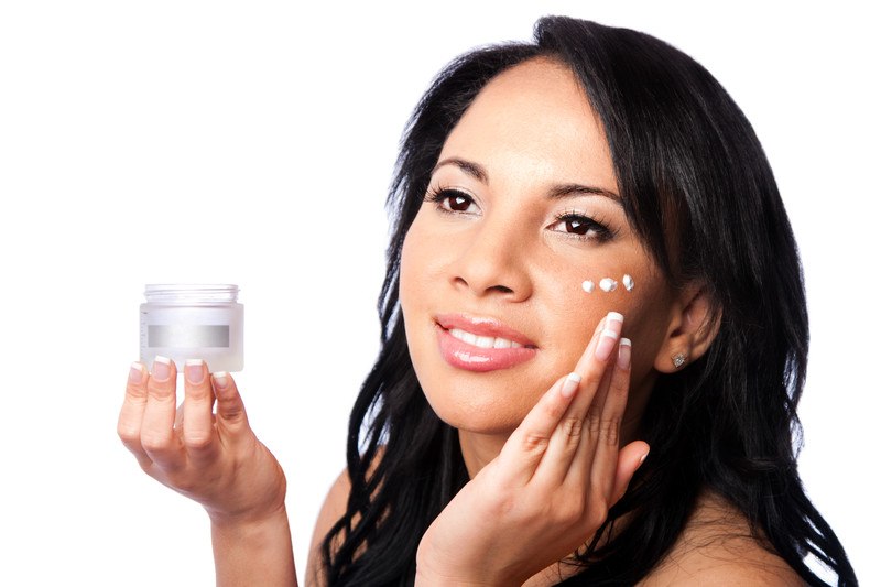 Young woman applying skincare in small dots under her eye,