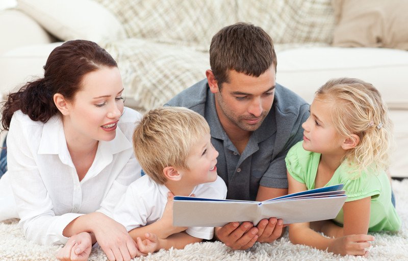 Young family reading a children's book on the floor