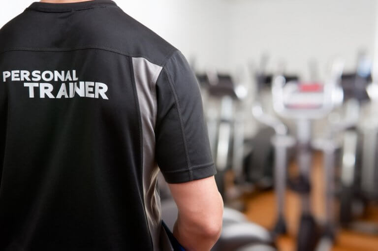 Personal trainer standing with his back to the camera in a gym.