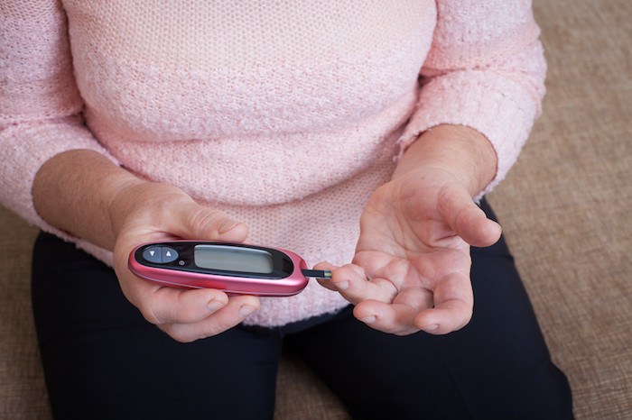 woman testing her blood sugar with electronic device representing diabetes related affiliate programs