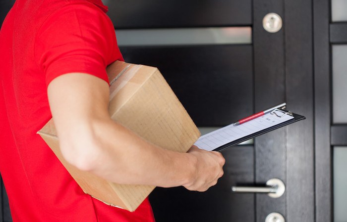 young man in a red shirt delivering packages to a door as a side gig to make extra money in the gig economy