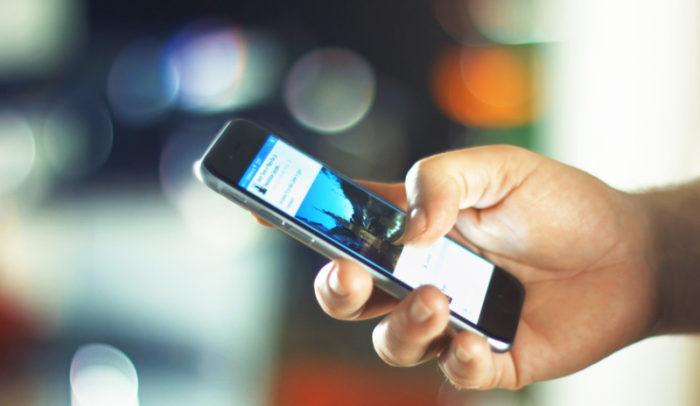 A person's hand using a phone and Facebook