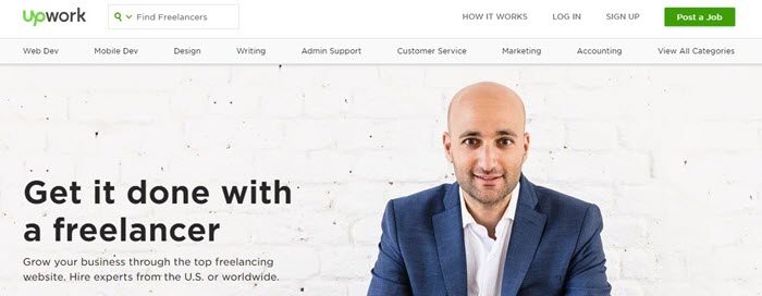 Upwork website screenshot showing an image of a bald man in a blue suit in front of a white brick wall. 