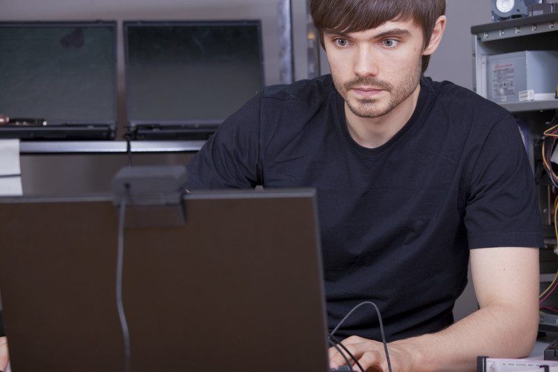 Image of a young man in a black shirt typing on a computer