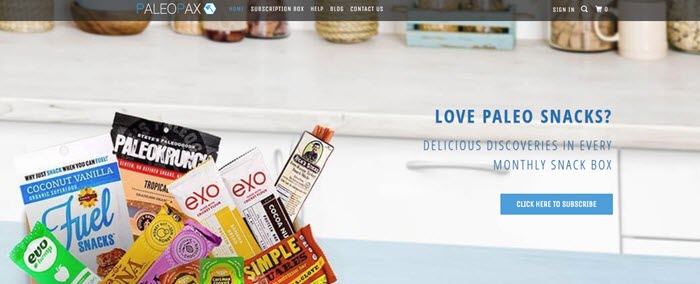 PaleoPax website screenshot showing the open box with snacks on a kitchen counter. 