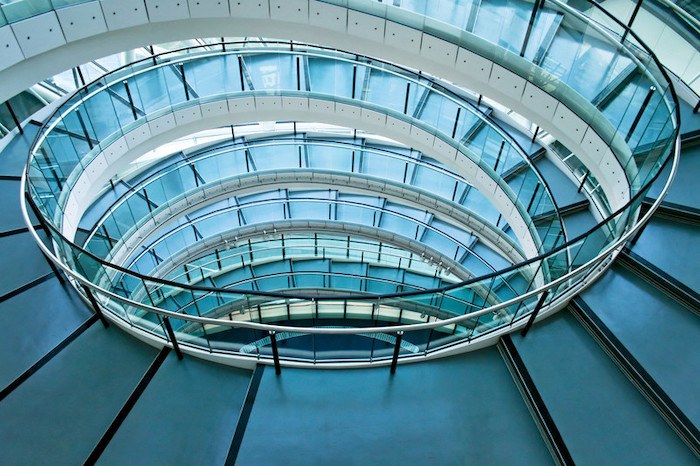 spiral staircase leading down in office building showing sublevels, and representing the concept of subdomains