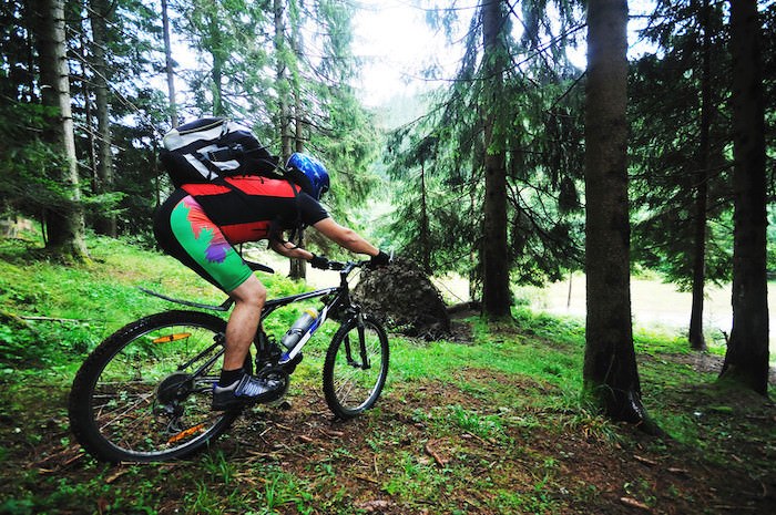 man mountain biking through the forest