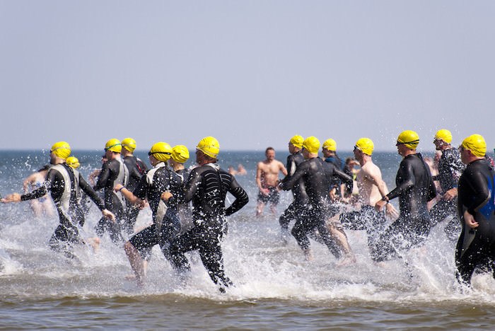 group of people in wet suits and caps read to compete in the swimming portion of the triathlon