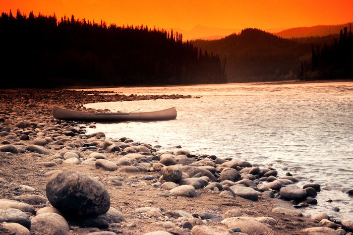 lonely canoe by itself with a sunset lake and mountains in the background representing the best mental health affiliate programs