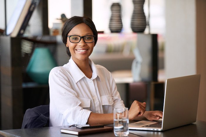 young black woman sitting at a cafe who looks like she's doing her taxes to represent the best personal finance affiliate programs