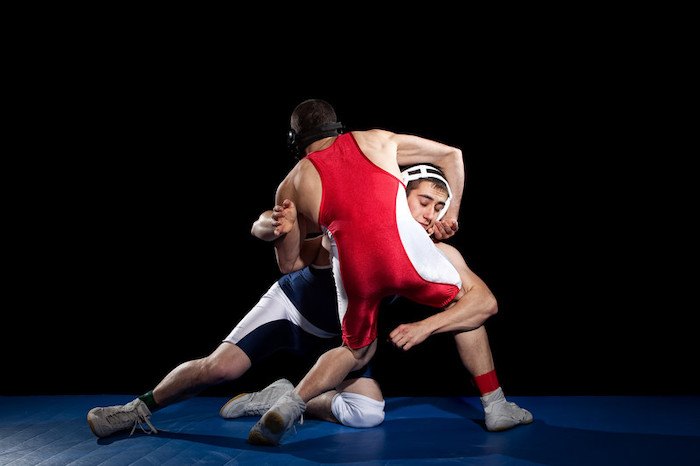 one man wearing red wrestling with one man wearing blue on a mat representing the best wrestling affiliate programs