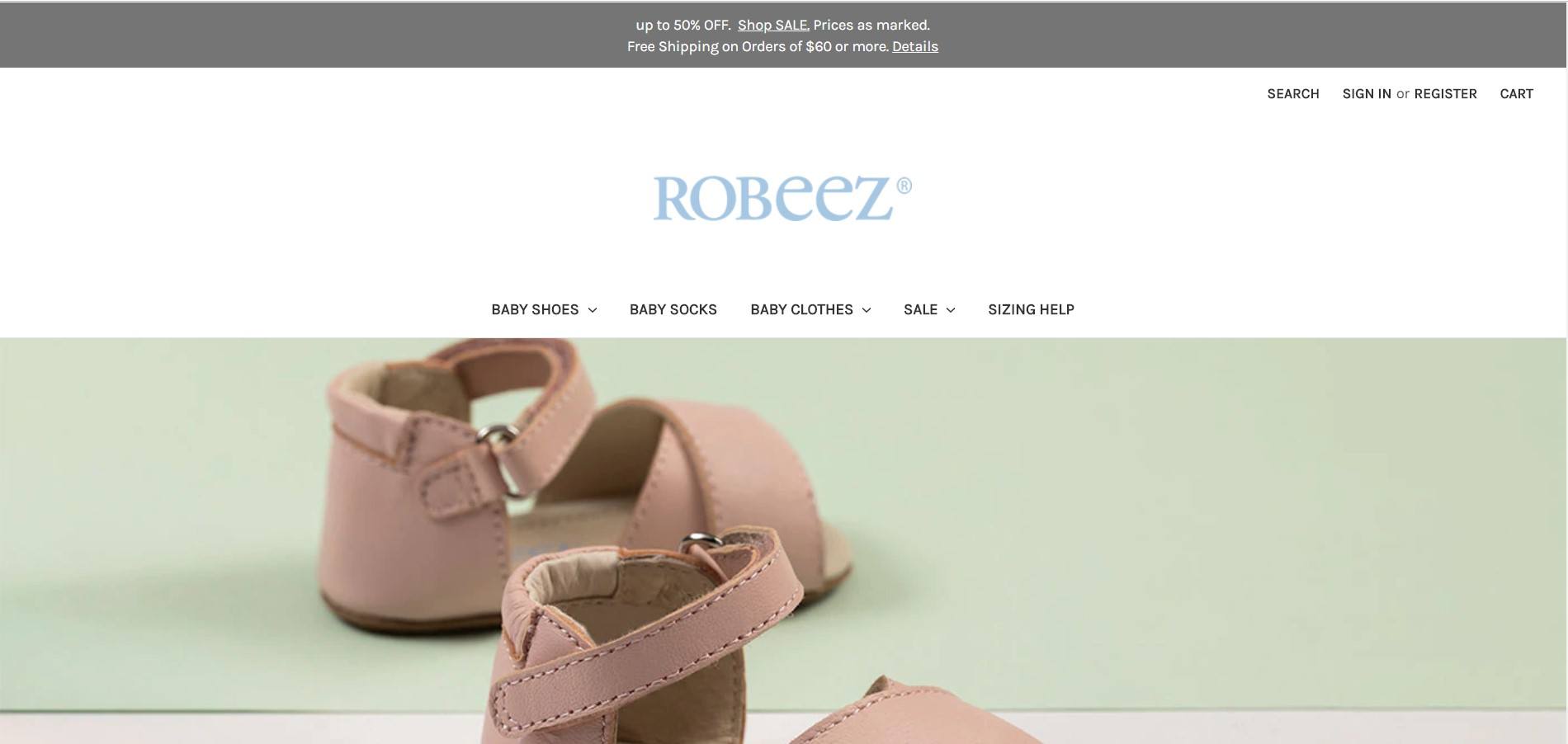 In this screenshot, a pair of brown baby sandals sit against a green background.