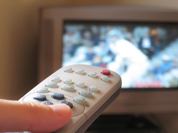 closeup of tv remote with sports playing in the background representing best cable tv affiliate programs