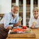 Older couple enjoying wine together in kitchen representing retired people who aren't ready to stop working