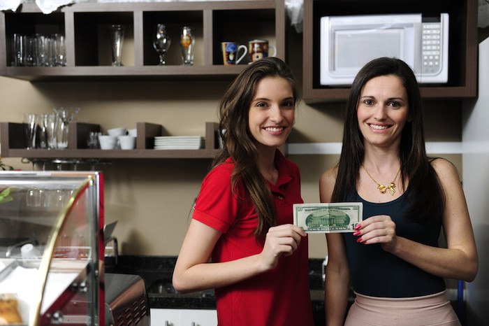 two young women entrepreneurs holding a dollar in a coffee shop representing the best small business loan affiliate programs