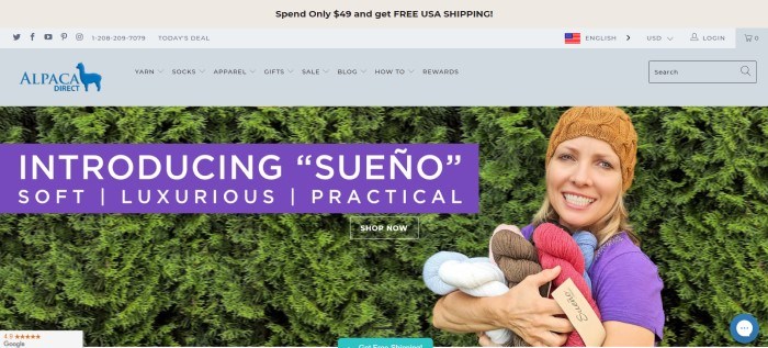 This screenshot of the home page for Alpaca Direct shows a smiling woman in a tan knitted beanie hat, standing near a tall green hedge with her arms full of Sueno skeins of yarn in a variety of colors, and in front of that is a purple text bar that introduces the 'Sueno' type of yarn.