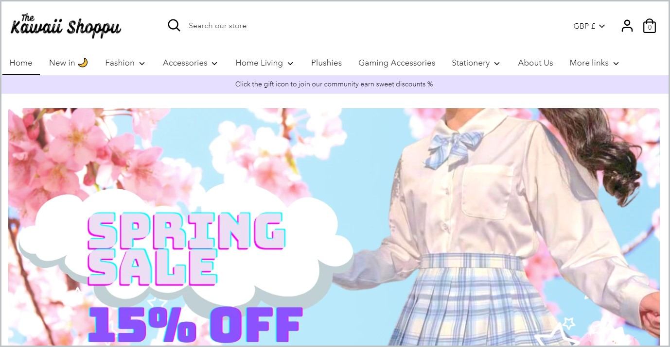 screenshot of The Kawaii Shoppu homepage showcasing a partial image of a girl in white long-sleeved top and white and blue checkered skirt school uniform and pink cherry blossoms