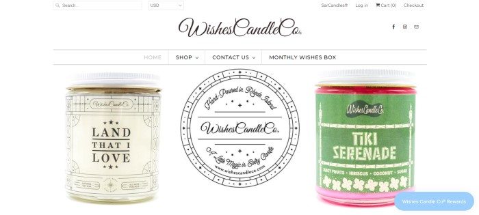 This screenshot of the home page for Wishes Candle Co. shows a cream-colored candle jar on the left and a green-colored candle jar on the right on a white background, with the company logo between them.