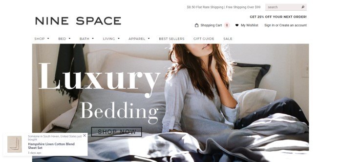 This screenshot of the home page for Nine Space includes a woman in a white shirt sitting on a bed with white, gray, and black bedding, along with white text announcing luxury bedding and a black 'shop now' call-to-action button. 