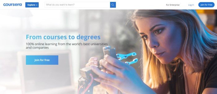 This screenshot of the home page for Coursera has a background photo of a woman working on a piece of computer equipment, behind blue text that reads 'From courses to degrees', along with an advertisement for Coursera classes and a blue call-to-action button.