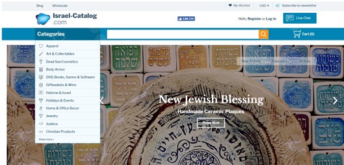 This screenshot of the home page for Israel catalog has a white background, blue header, and white drop-down text boxes with black lettering displaying the categories of goods sold here, next to a large photo of hand-made ceramic plaques with Hebrew writing on them, painted in a variety of colors. 