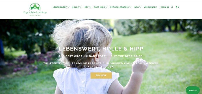 This screenshot of the home page for Organic Baby Foods includes a large photo of a blonde toddler girl in a white dress walking away from the camera across a green lawn. 