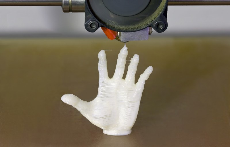 This image shows a model of an outstretched hand made of some white substance as it is being printed by a 3D printer, representing the best 3D printer affiliate programs.